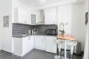 una cocina con armarios blancos y una mesa pequeña. en Beau studio près de la TOUR EIFFEL / ROLAND GARROS en Boulogne-Billancourt