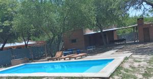 a swimming pool with two benches and a fence at Finca La Huella II in Santiago del Estero