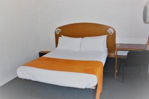 1 cama con cabecero de madera y escritorio en Hôtel Quick Palace Valence Nord, en Bourg-lès-Valence