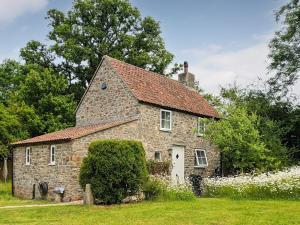 una vecchia casa in pietra con tetto rosso di Honeymead Cottage a Wick