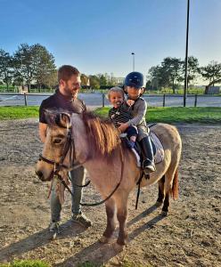 a man holding a child on a horse with a man holding a baby at gite Tombelaine in Pontorson