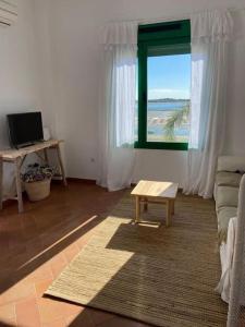 Apartamento en primera línea de playa في إل رومبيدو: غرفة معيشة مع نافذة وأريكة وطاولة
