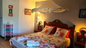 a bedroom with a bed with a floral bedspread at Ti Studio Creole Mahogany in Sainte-Anne