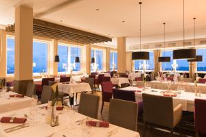 a restaurant with white tables and chairs and windows at Hotel Bavaria in Zwiesel