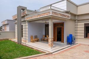 uma casa branca com um pátio com cadeiras azuis em Cheerful 4-bedroom home with parking em Bujumbura