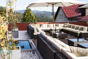 a patio with couches and an umbrella and a pond at Hotel Bavaria in Zwiesel