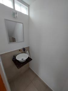 Baño blanco con lavabo y espejo en departamento temporario en Esquel