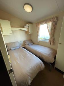 two beds in a small room with a window at Mawson Retreat Dog Friendly Static Caravan in Millom