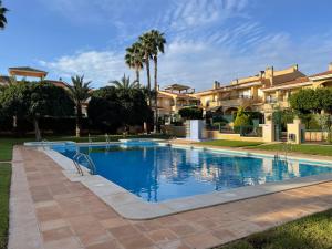 a swimming pool in front of a building with palm trees at Modern Apartman - Novamar 1 in Gran Alacant