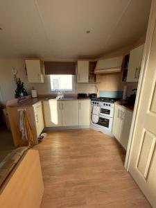 a small kitchen with white cabinets and a stove at Mawson Retreat Dog Friendly Static Caravan in Millom