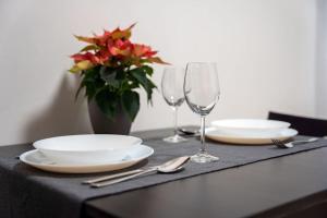 uma mesa com pratos e copos e um vaso com flores em Byt Krenova 1+kk em Brno