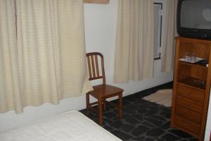 1 dormitorio con 1 cama, 1 silla y TV en Quarto pequeno 515 do Monte dos Arneiros, en Lavre