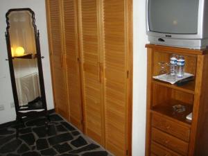 a room with a television and a wooden closet at Quarto pequeno 515 do Monte dos Arneiros in Lavre