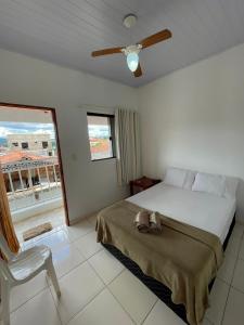 a bedroom with a bed and a chair and a window at Pouso Dona Ana in Pirenópolis