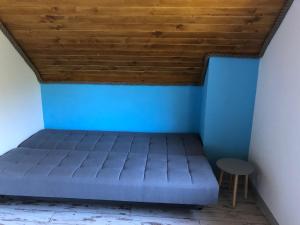 a bed in a room with a blue wall at Pod Lasem in Czarny Młyn