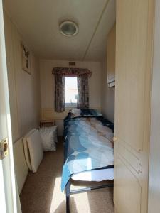 1 dormitorio con cama y ventana en Pet friendly Holiday Caravan sleeps 5 en Hemsby