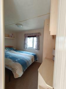 Habitación pequeña con cama y ventana en Pet friendly Holiday Caravan sleeps 5 en Hemsby