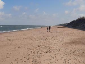 dos personas caminando en una playa cerca del océano en Pet friendly Holiday Caravan sleeps 5 en Hemsby