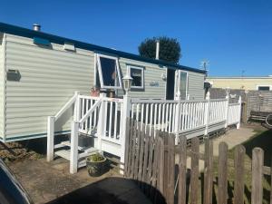 uma casa móvel com um alpendre branco e uma cerca em Pet friendly Holiday Caravan sleeps 5 em Hemsby