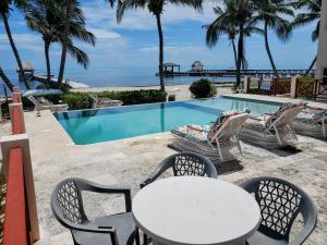 a table and chairs next to a swimming pool at Miramar Villas Resort in San Pedro