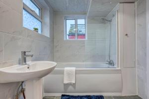 a white bathroom with a sink and a bath tub at Stylish & Cosy in Coventry Garden Parking in Coventry +13 photos