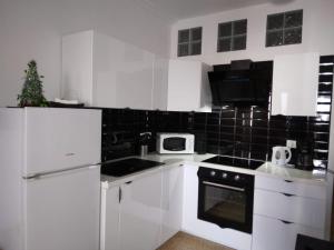 eine Küche mit weißen Geräten und einer schwarz gefliesten Wand in der Unterkunft Holiday Apartment in Playa del Ingles