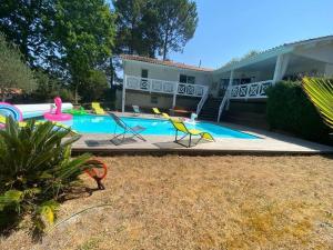 basen z krzesłami i dom w obiekcie VILLA LES PINS BISCA w mieście Biscarrosse
