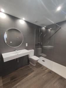 a bathroom with a sink and a toilet and a mirror at Apartamentos Turísticos Betanzos in Betanzos