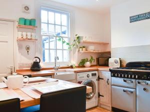 cocina con mesa, fogones y fregadero en Little Blue Seaside House en Scarborough