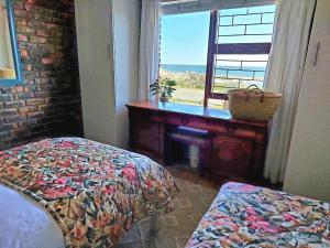 a bedroom with a bed and a desk and a window at La Mer Seafront Selfcatering Accommodation Kleinmond in Kleinmond