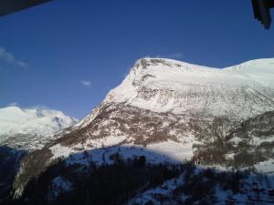 a mountain covered in snow with trees in front of it at Lunheim in Geiranger in Geiranger