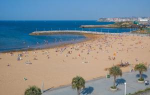 a crowd of people on a beach near the ocean at BRiSaS DeL NoRTe in Gijón