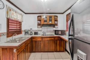 a kitchen with wooden cabinets and a black refrigerator at Lovely Condo (8 people): Pools, Tennis Courts, BBQ in Manuel Antonio