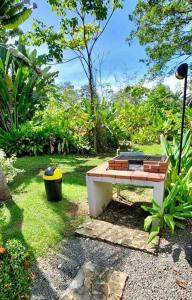 a picnic table sitting in the grass in a garden at Lovely Condo (8 people): Pools, Tennis Courts, BBQ in Manuel Antonio
