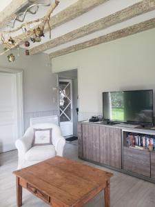 sala de estar con TV y mesa de centro de madera. en Chambre Zen à la campagne, en Marennes