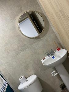 a bathroom with a mirror and a toilet and a sink at Providence Paradise Apartamento in Providencia