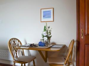 een tafel met twee stoelen en een vaas met bloemen erop bij Low Tide in Cellardyke