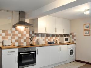 een keuken met witte kasten en een fornuis met oven bij Low Tide in Cellardyke