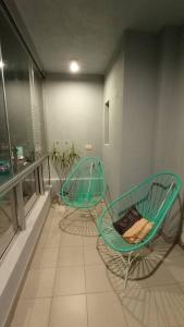 2 sillas verdes sentadas en un balcón en una habitación en Nb1 apartment free parking con cochera privada en Buenos Aires
