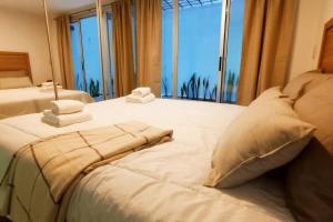 1 cama blanca grande con toallas y ventana en Nb1 apartment free parking con cochera privada en Buenos Aires