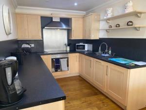 a kitchen with wooden cabinets and a black counter top at Spacious 2 bedroom apartment Cleethorpes in Cleethorpes