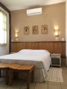 a bedroom with a large white bed and a bench at Pousada Aroeira in Barra do Sahy
