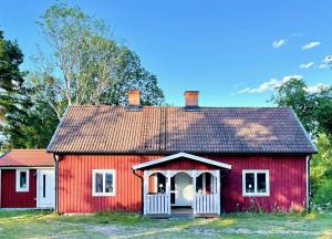 a red house with a white door and a roof at Lilla Hule - på landet nära sjö in Oskarshamn