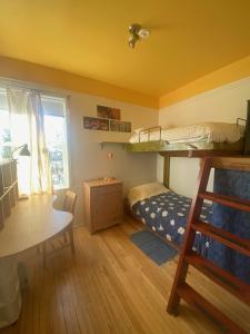 een slaapkamer met een stapelbed, een bureau en een tafel bij Auberge Internationale Le Tangon in Sept-Îles