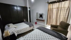 una camera da letto con due letti, una sedia e una finestra di Departamento céntrico y acogedor a Zacatecas