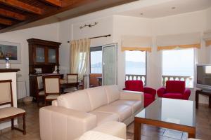 a living room with a white couch and red chairs at Pampas Seafront villa, 6 bedrooms, North Evvoia in Kanatádhika