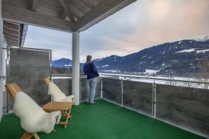 un hombre parado en un balcón con dos sillas en Berg Apartment-Berg im Drautal en Berg im Drautal