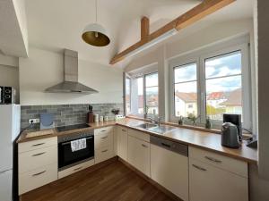 cocina con armarios blancos y ventana grande en Dachgeschosswohnung en Lörrach