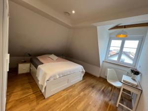 Schlafzimmer mit einem Bett, einem Schreibtisch und einem Fenster in der Unterkunft Dachgeschosswohnung in Lörrach