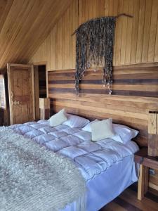 un grande letto in una camera con pareti in legno di ALMA CHILOTA a Castro